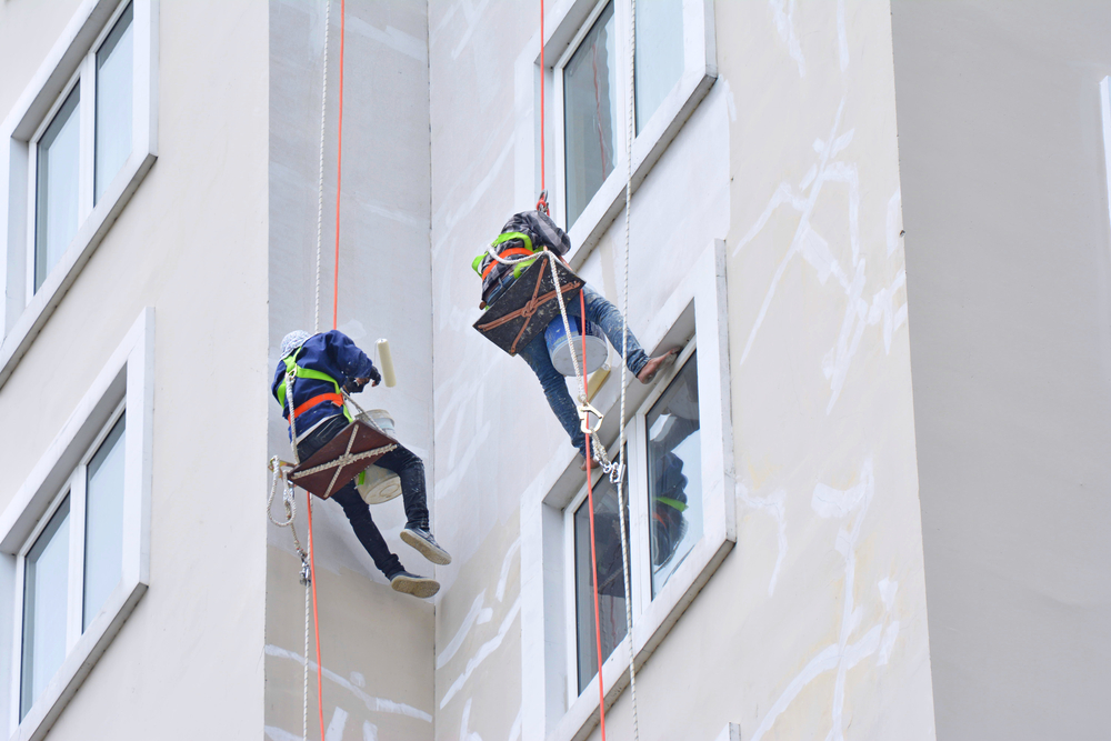 asian,painters,are,hanging,to,paint,with,high,building